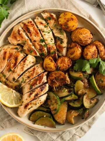 quick marinated chicken breast served with potatoes and zucchini on a plate.