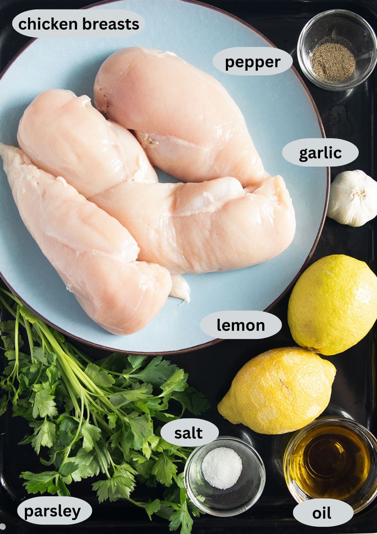 labeled ingredients for cooking quick marinated chicken breast with lemons, garlic and parsley.
