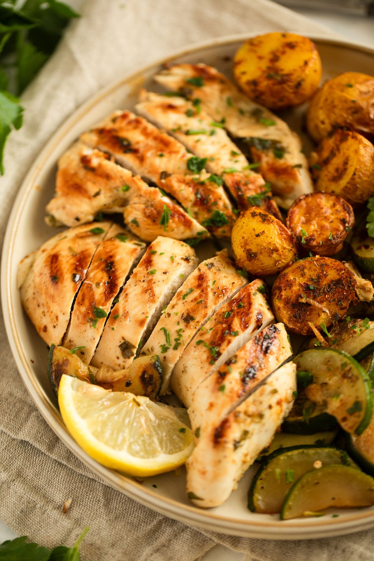 sliced quick marinated chicken breast with lemon wedges on a plate.