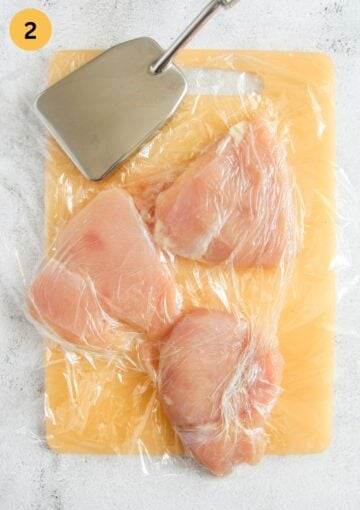 pounding chicken breast between two sheets of plastic wrap with a meat mallet.