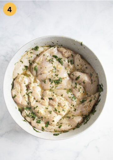 chicken breasts marinating in a lemon, garlic and parsley marinade.