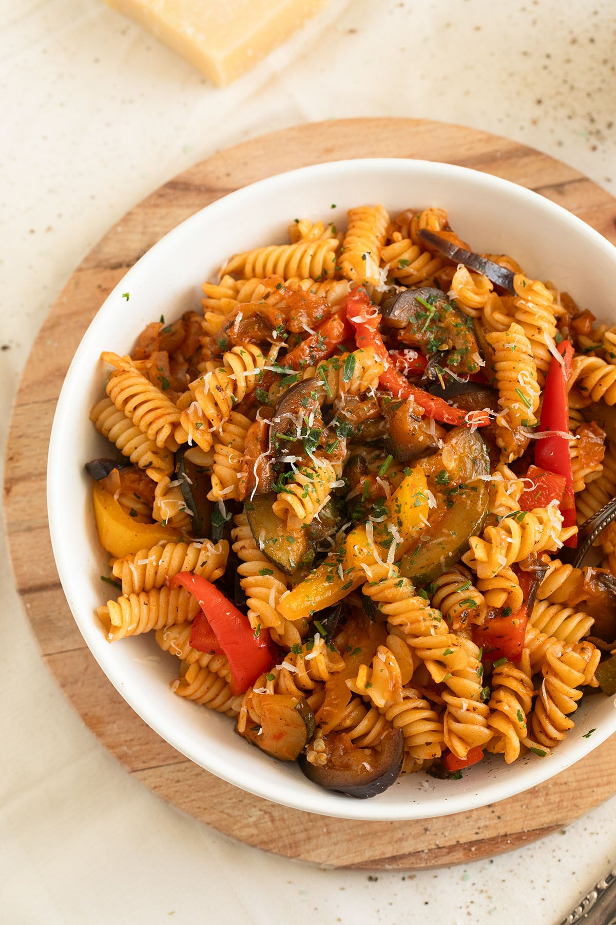 pasta with ratatouille on a plate on a round wooden cutting board.