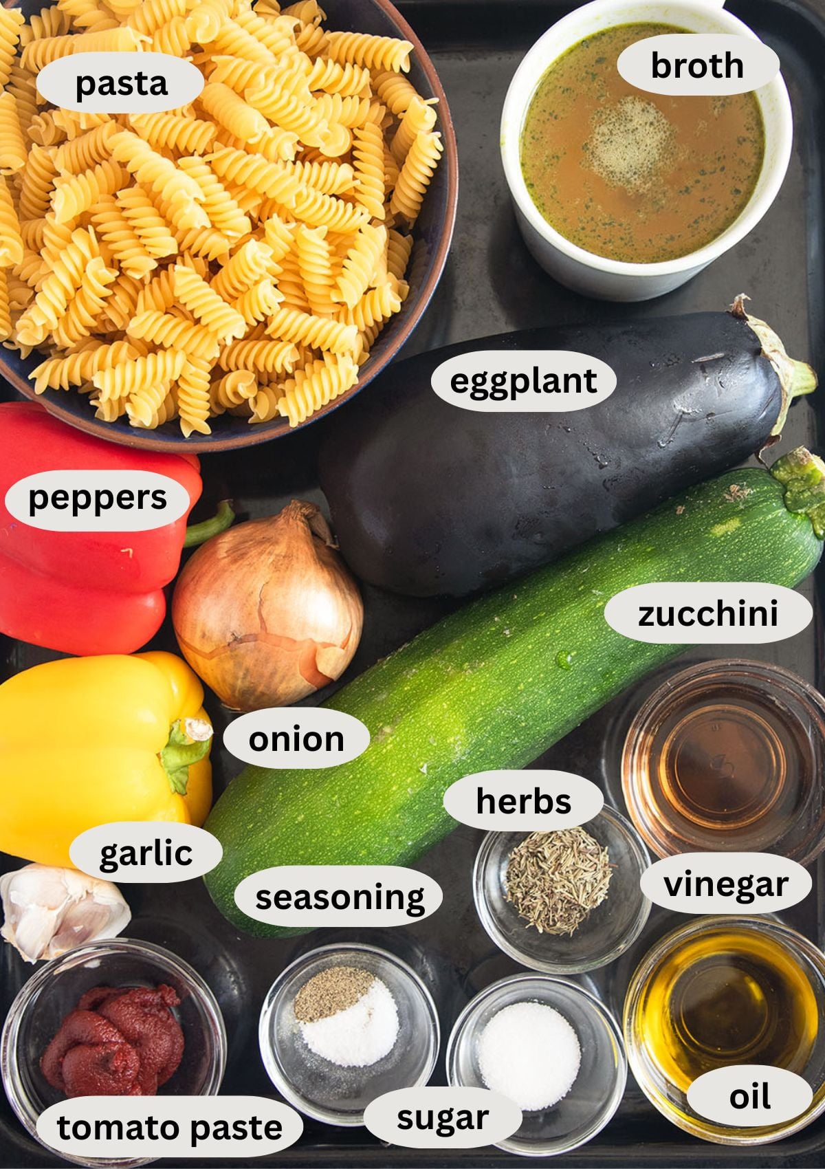 labeled ingredients for making ratatouille with pasta, eggplant, peppers, onion, zucchini, and broth.