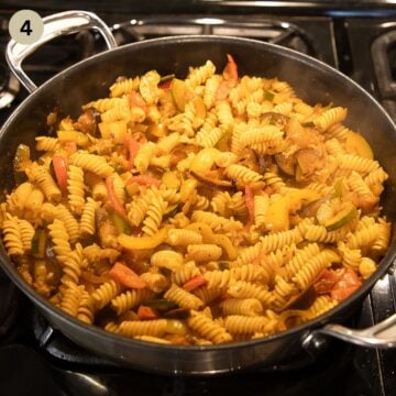 mixing ratatouille and pasta in a large pan on the stove.