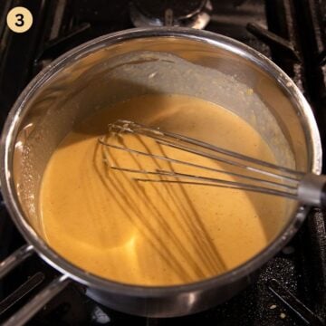 whisking beer cheese dip with a egg whisk in a small saucepan