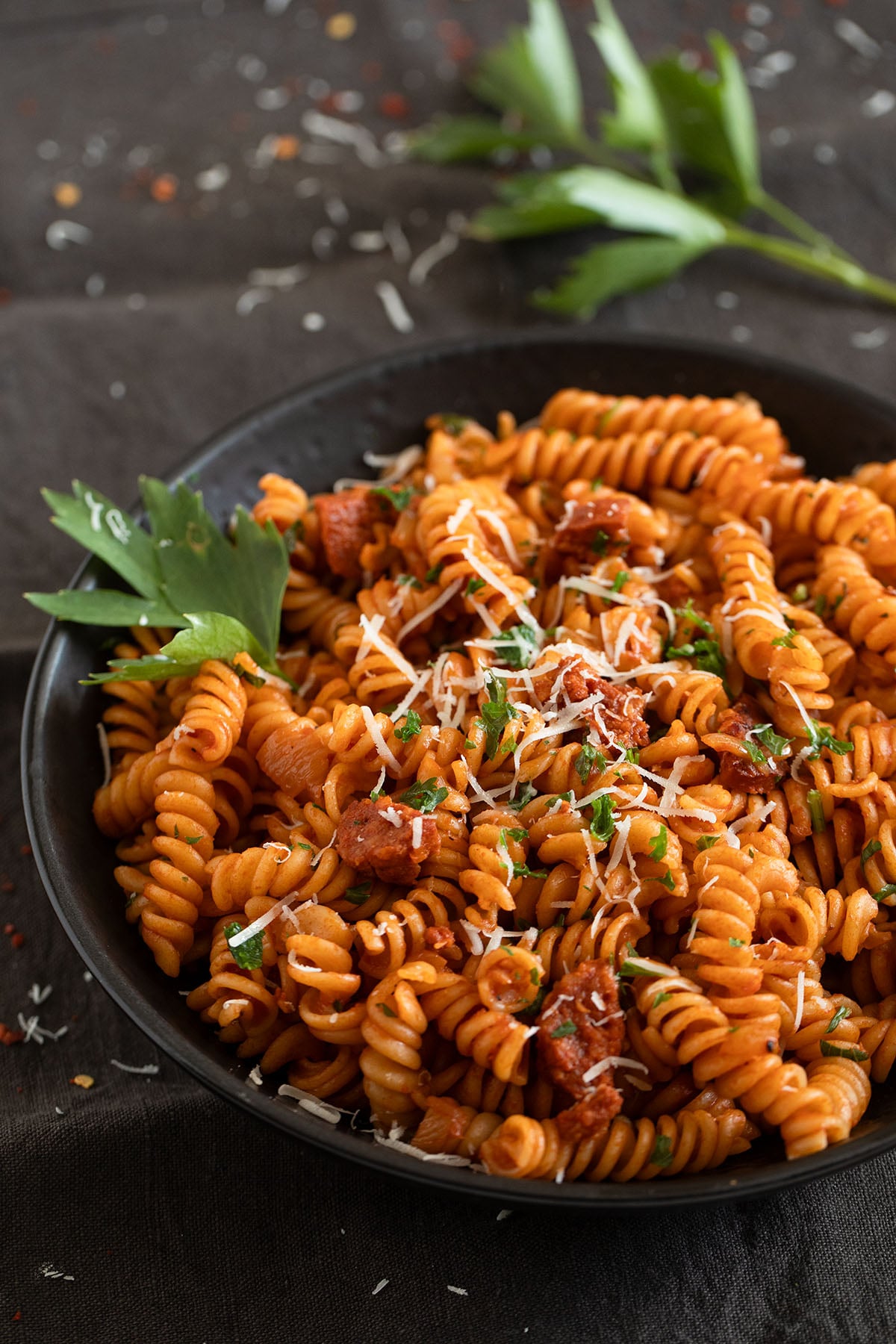 bowl full of chorizo pasta sprinkled with parsley and parmesan.