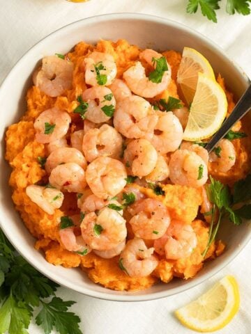 shrimp and sweet potato mash served with lemon wedges in a bowl.