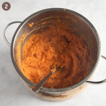 stirring mashed sweet potatoes in a pot with a spoon.