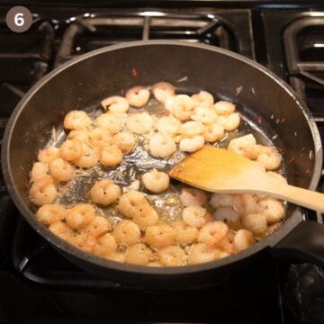 stirring shrimp with butter in a skillet.