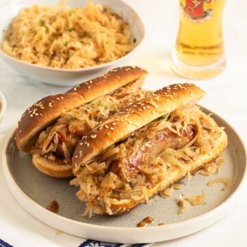 two bratwurst sandwiches, a bowl of sauerkraut and a glass of beer.
