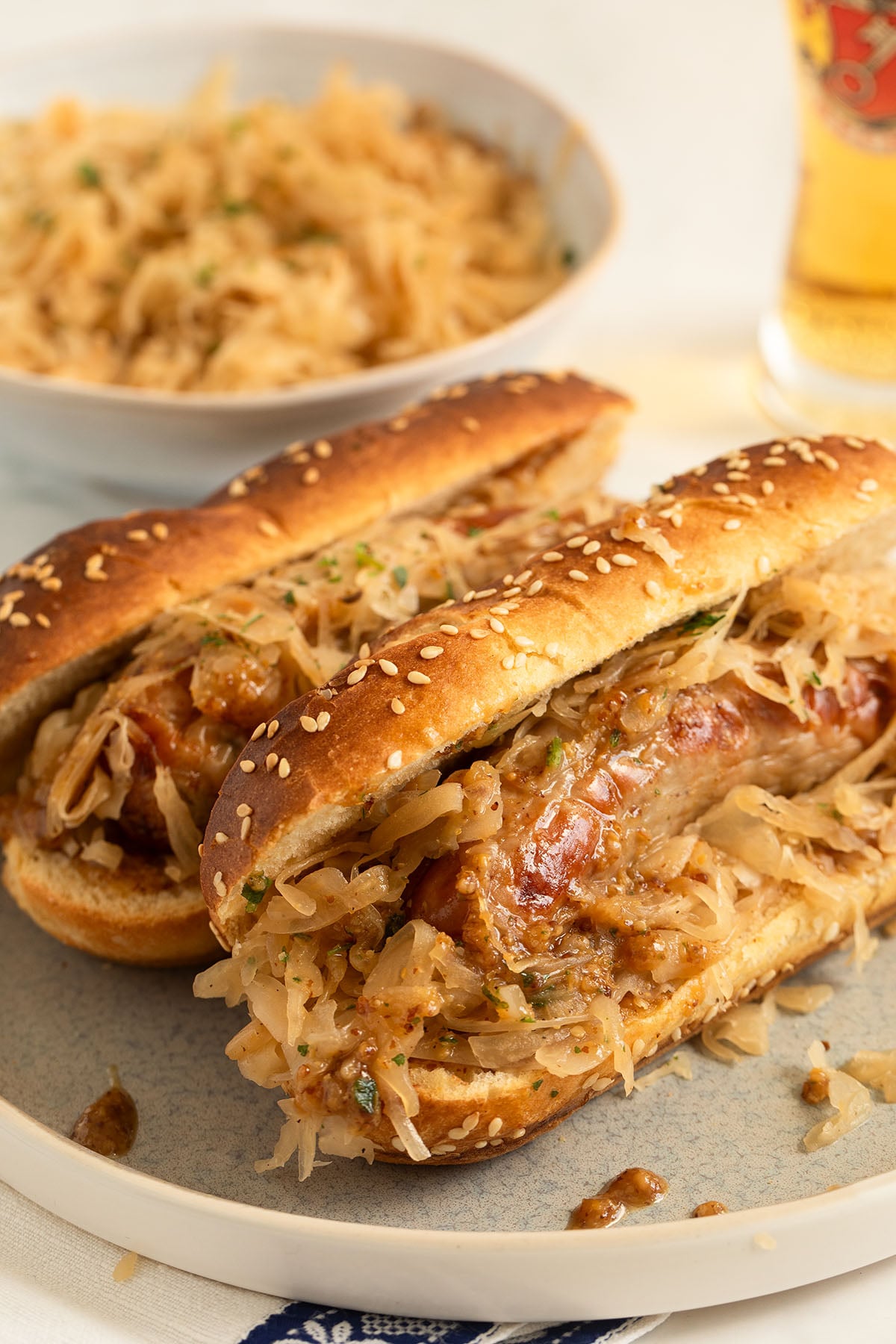 bratwurst sandwiches with sauerkraut in long pretzel buns on a plate.