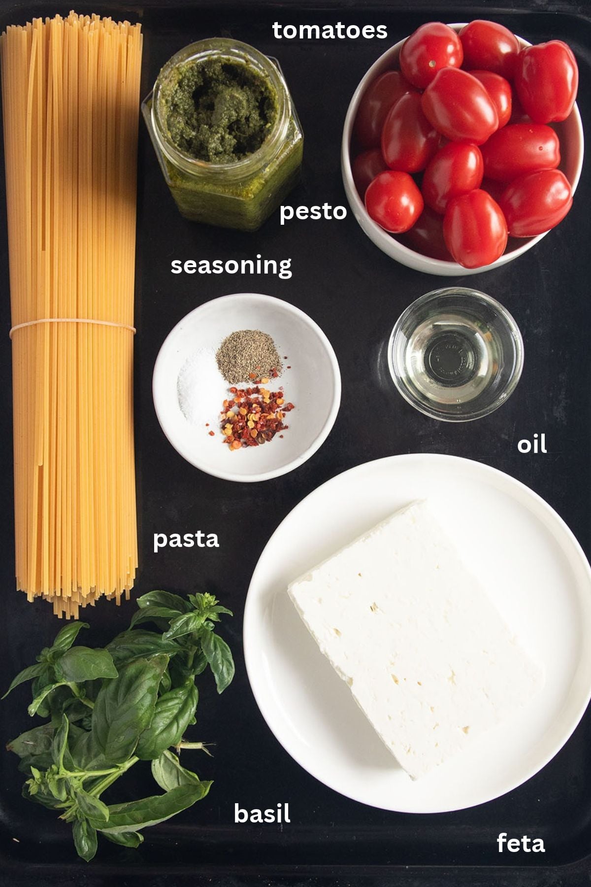 labeled ingredients for making spaghetti with pesto, feta, tomatoes, and fresh basil.