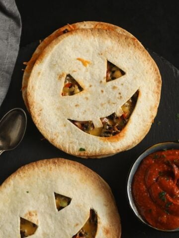 two halloween quesadillas with smilling jack'o'lantern faces and salsa.