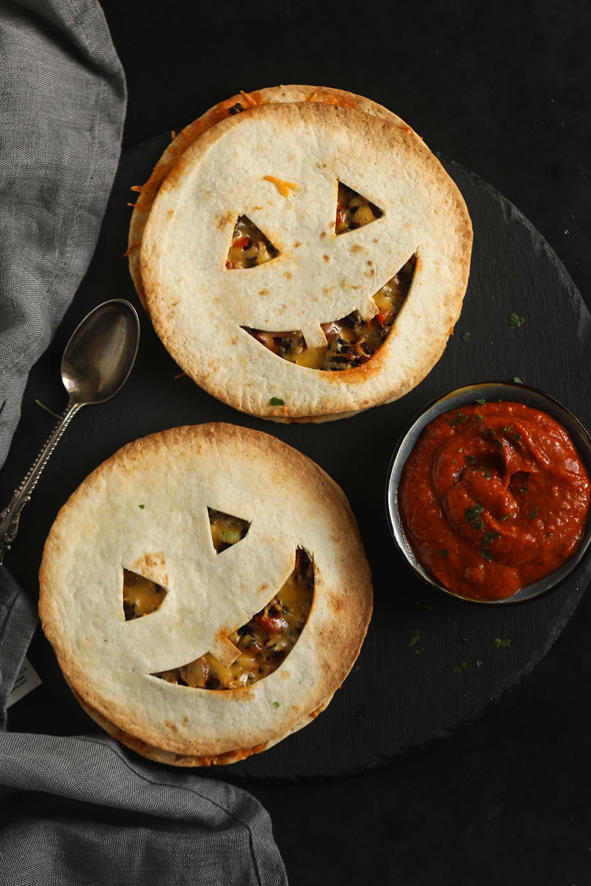 two jack'o'lantern-faced quesadillas and a small bowl of salsa.