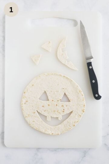 Cutting jack-o'-lantern faces into small tortillas for the quesadillas.