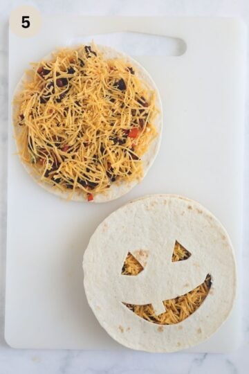 assembling halloween quesadillas with chorizo and cheddar filling and funny face top.