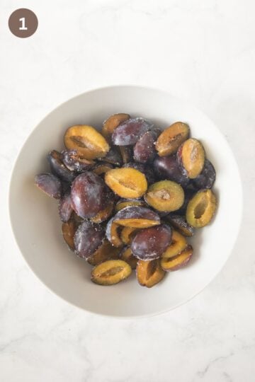 stoned and halved italian plums for cake in a bowl.