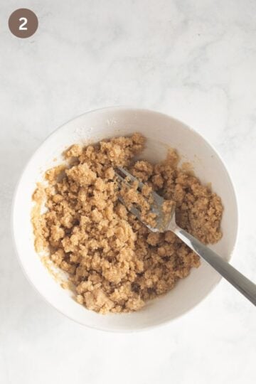 stirring crumbles for cake with a fork in a bowl.